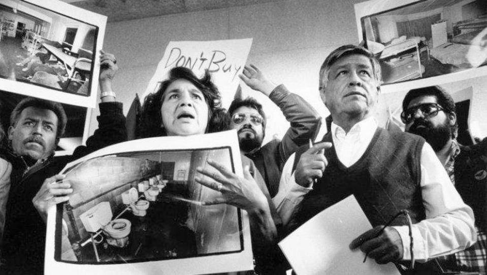 United Farm Workers leaders Dolores Huerta and Cesar Chavez display photos of the conditions that farmworkers endure in San Joaquin Valley farm labor camps at a news conference outside U.S. District Court in Fresno on Tuesday, Nov. 21, 1989.