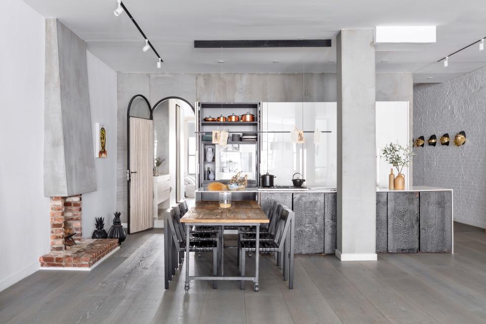 In the kitchen, lustrous white Boffi cabinetry offsets concrete accents and a marble-topped shou sugi ban island. Nachum’s Melissa resides next to a fireplace and steel-and-glass arched door by Mercer Project.