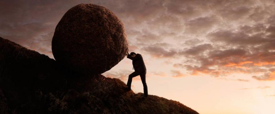 man pushing a boulder up a hill. myth of sisyphus concept.