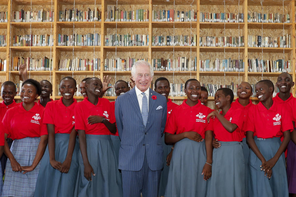 Britain's King Charles III, center, poses for a photograph with secondary school students during his visit to the Eastlands Library to learn about a project that restores old libraries and encourages reading amongst children in the community in Makadara district of Nairobi, Tuesday, Oct. 31, 2023. King Charles is in Kenya for a four-day trip, his first state visit to a Commonwealth country as monarch, underscoring his commitment to an organization that's been central to Britain's global power and prestige since World War II. (Thomas Mukoya/Pool Photo via AP)