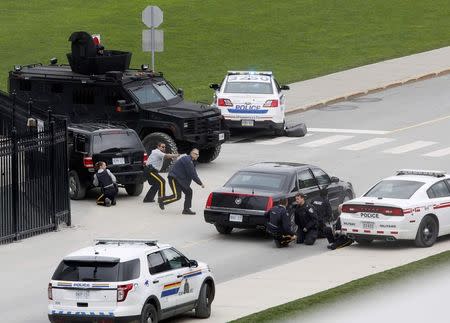 Police officers take cover near Parliament Hill following a shooting incident in Ottawa October 22, 2014. REUTERS/Chris Wattie