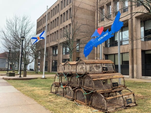 The Nova Scotia flag flies at half-mast beside a display of solidarity in front of the P.E.I. government offices in Charlottetown Sunday. (Shane Ross/CBC - image credit)