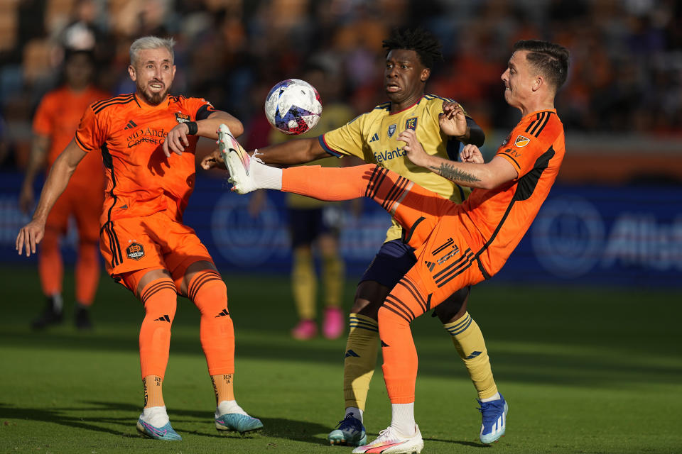 Houston Dynamo forward Corey Baird (11) kicks the ball away from Real Salt Lake midfielder Emeka Eneli, center, during the first half of an MLS playoff soccer match, Sunday, Oct. 29, 2023, in Houston. (AP Photo/Kevin M. Cox)