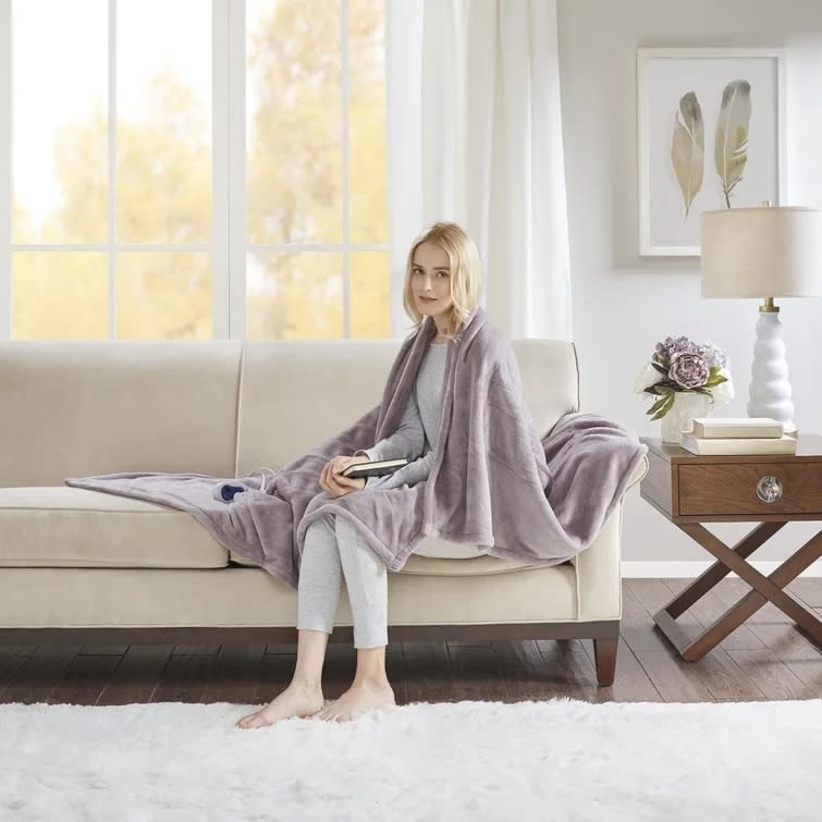 A model wearing the oversized plush heated throw blanket