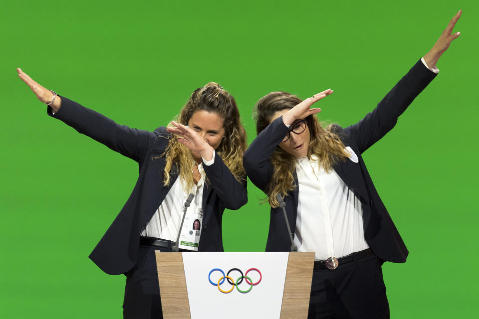 FILE - In this Monday, June 24, 2019 filer, Italian snowboarder Michela Moioli, left, and Italian skier Sofia Goggia, right, dab after speaking during the presentation of the Milan-Cortina candidate cities the first day of the 134th Session of the International Olympic Committee (IOC), in Lausanne, Switzerland. Eight months later Goggia and Moioli feel like their worlds are crumbling apart as they are locked inside their homes just a few miles apart in the Bergamo area of northern Italy that is struggling to keep up with the coronavirus, they are surrounded by death and despair. For most people, the new coronavirus causes only mild or moderate symptoms. For some it can cause more severe illness. (Laurent Gillieron/Keystone via AP, File)