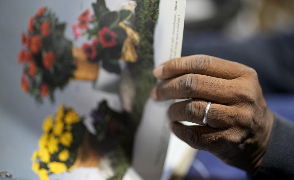 Tony Kinard, who runs Dot's Flower Shop, holds a catalog of different flower arrangements, Tuesday, May 2, 2023, in Bamberg, S.C. Kinard, a President Joe Biden supporter, said the president has plenty of legislative wins to promote, including the Inflation Reduction Act, the roughly $740 billion program to promote clean energy, reduce prescription drug costs, shore up the health insurance marketplace and tax large corporations. He would like to see action on gun control, especially as it edges closer to his home about an hour’s drive south of Columbia in rural Bamberg, where he runs Dot’s Flower Shop. (AP Photo/Chris Carlson)