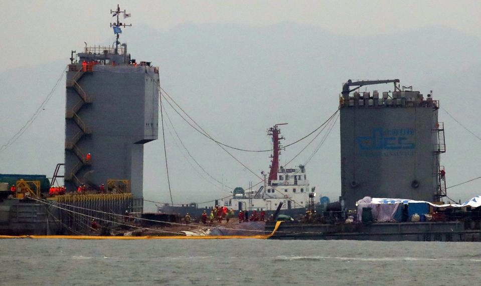 Workers prepare to lift the sunken Sewol ferry in waters off Jindo, South Korea, Thursday, March 23, 2017. South Korean workers on Thursday slowly pulled up a 6,800-ton ferry from the water, nearly three years after it capsized and sank into the violent seas off South Korea's southwestern coast, an emotional moment for a country that continues to search for closure to one of its deadliest disasters ever. (Lee Jin-wook/Yonhap via AP)