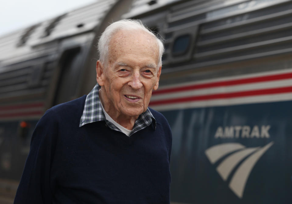 Nelson Soule, 91, poses next to the Amtrak Downeaster train Wednesday, Oct. 31, 2012 at the station in Portland, Maine. Soule will be aboard Amtrak's Downeaster on Thursday as the Boston-to-Portland service expands northward to Freeport and Brunswick for the first time in more than 50 years. (AP Photo/Joel Page)