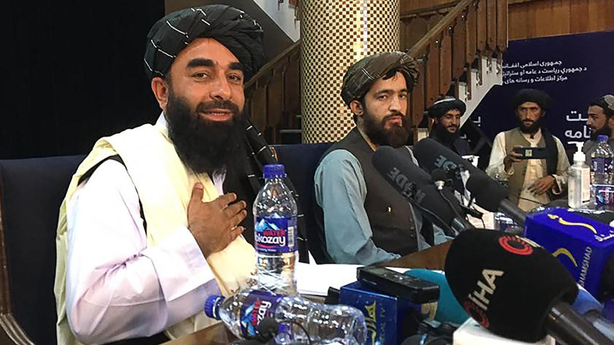 Taliban spokesman Zabihullah Mujahid, left, arrives to hold the first press conference in Kabul on Tuesday after the Taliban's swift takeover of Afghanistan.