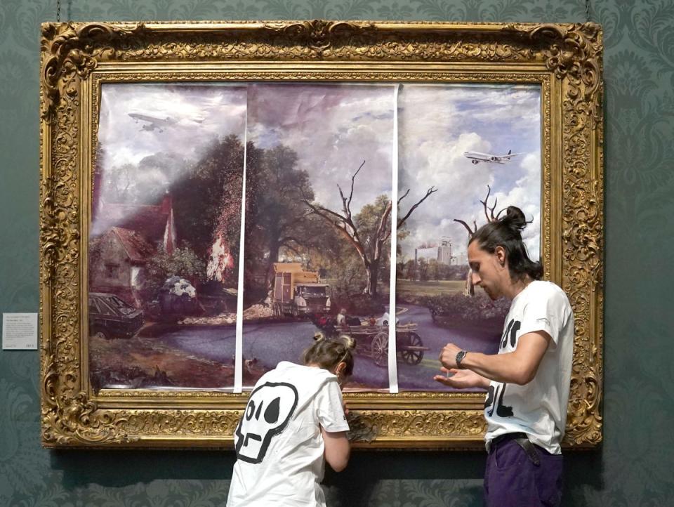 Protesters from Just Stop Oil climate protest group, cover John Constable’s The Hay Wain with their own picture at the National Gallery, London (PA) (PA Wire)