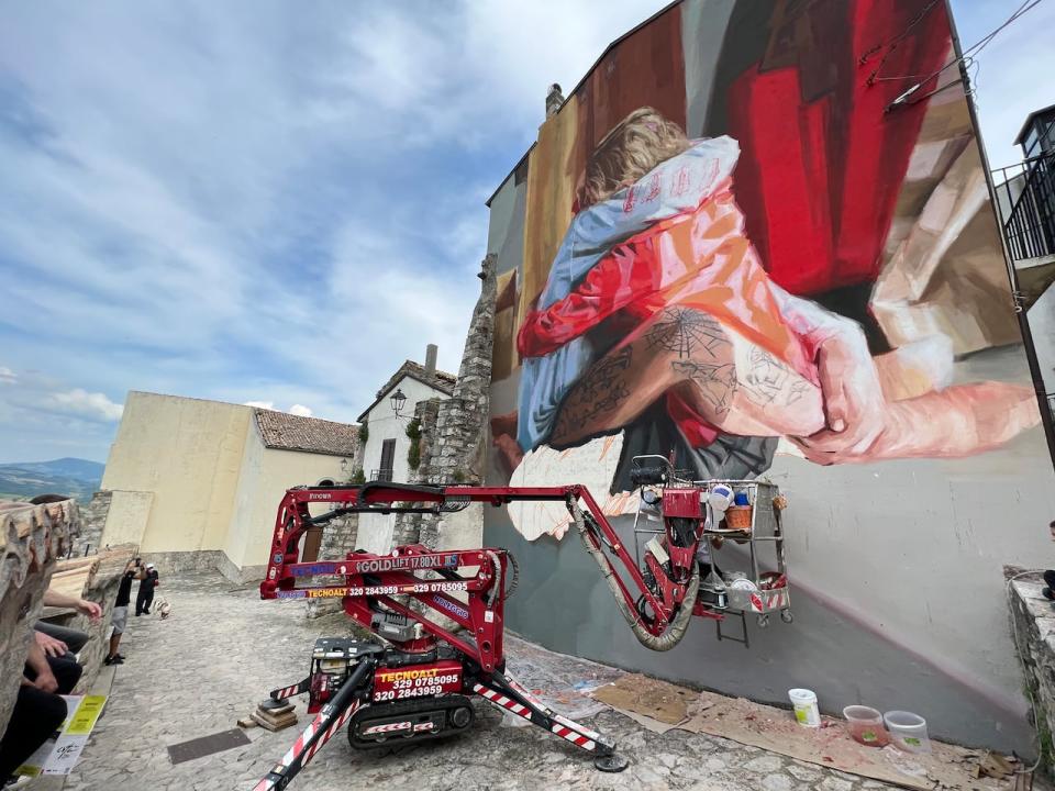 A mural in progress is shown on a wall in Civitacampomarano, Italy.