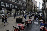 Diners eat at tables on the pedestrian walkway Madero, where temporary pandemic rules have allowed street tables and retail displays, in central Mexico City, Friday, Feb. 12, 2021. The city's mayor announced Friday that the capital will lower the COVID-19 pandemic alert level from red to orange next week, permitting some long-closed businesses including gyms and indoor pools to reopen with capacity restrictions and distancing. (AP Photo/Rebecca Blackwell)