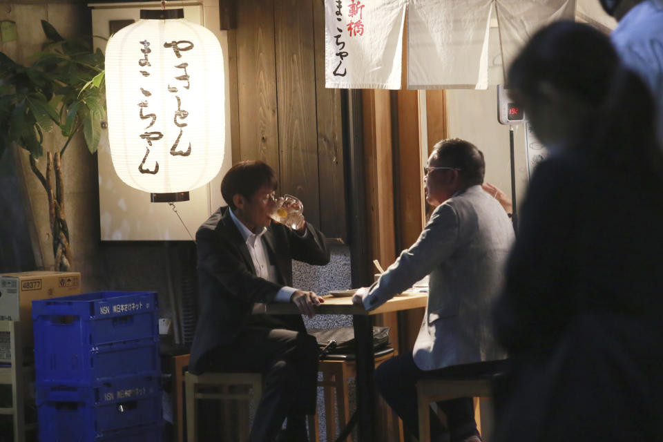 FILE - In this Oct. 4, 2021, file photo, people enjoy drinks at a bar following the end of the current coronavirus state of emergency restrictions, in Tokyo. People in Tokyo could eat and drink inside bars and restaurants for longer evening hours starting Monday, Oct. 25, 2021 as officials eased social distancing rules with the country’s daily coronavirus cases reaching its lowest levels in more than a year. (AP Photo/Koji Sasahara, File)