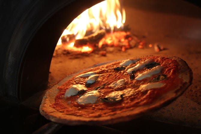 A gluten-free pizza emerges from the wood-fired pizza oven at Basta.