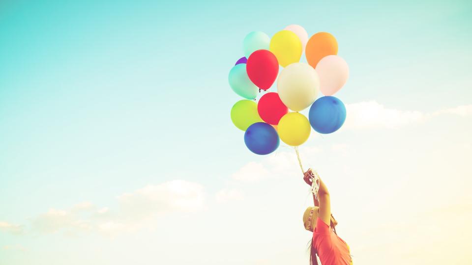 Girl hand holding multicolor balloons done with a retro instagram filter effect, concept of happy birth day in summer and wedding honeymoon party, Vintage color tone style.