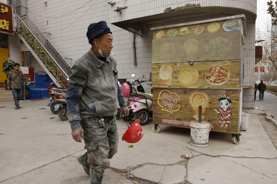 A worker walks past a closed street stall in Aksu in western China's Xinjiang Uyghur Autonomous Region on March 18, 2021. China is going global with its campaign to deflect criticism over its policies in the northwestern region of Xinjiang. The region's government on Wednesday, June 2, organized a transcontinental zoom call showcasing economic development and poverty elimination. (AP Photo/Ng Han Guan)