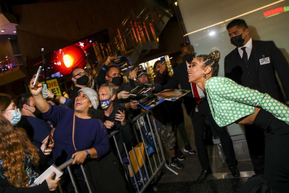 fans behind a barricade take selfies with a celebrity