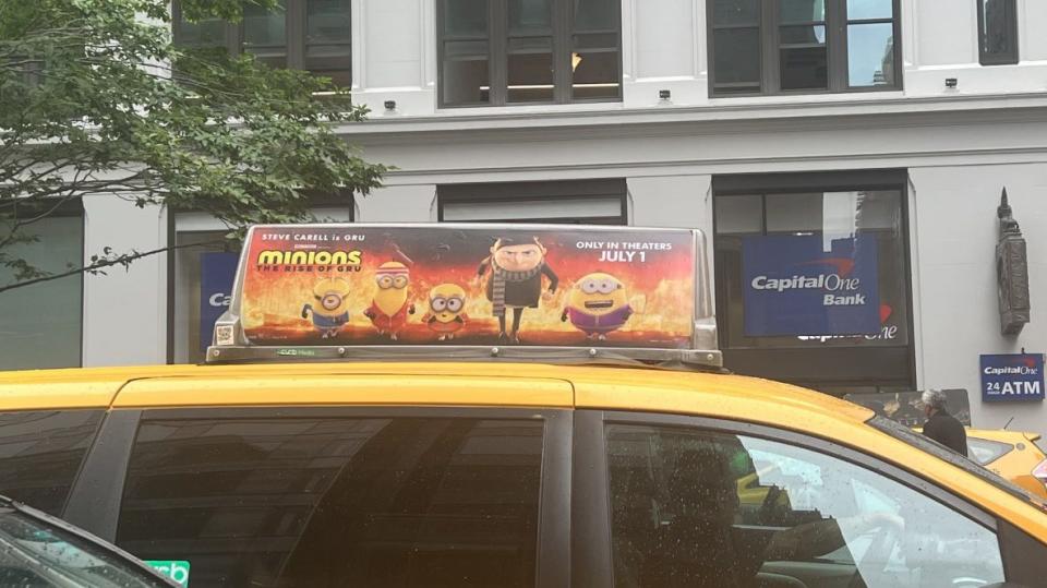 A taxi movie poster touts that “Minions” is playing “only in theaters.”