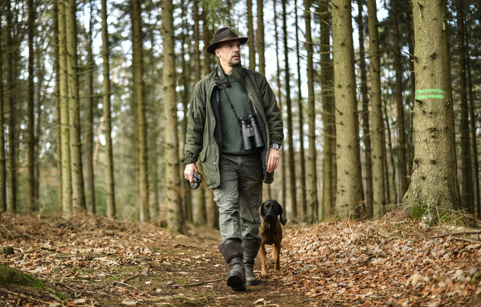 In this Dec. 7, 2018 photo Dirk Gratzel walks with his dog at his hunting ground in Stollberg, western Germany. Gratzel counts his carbon emissions. The software entrepreneur from Germany is among a growing number of people looking for ways to cut their personal greenhouse gas emissions from levels that scientists say are unsustainable if global warming is to be curbed. (AP Photo/Martin Meissner)