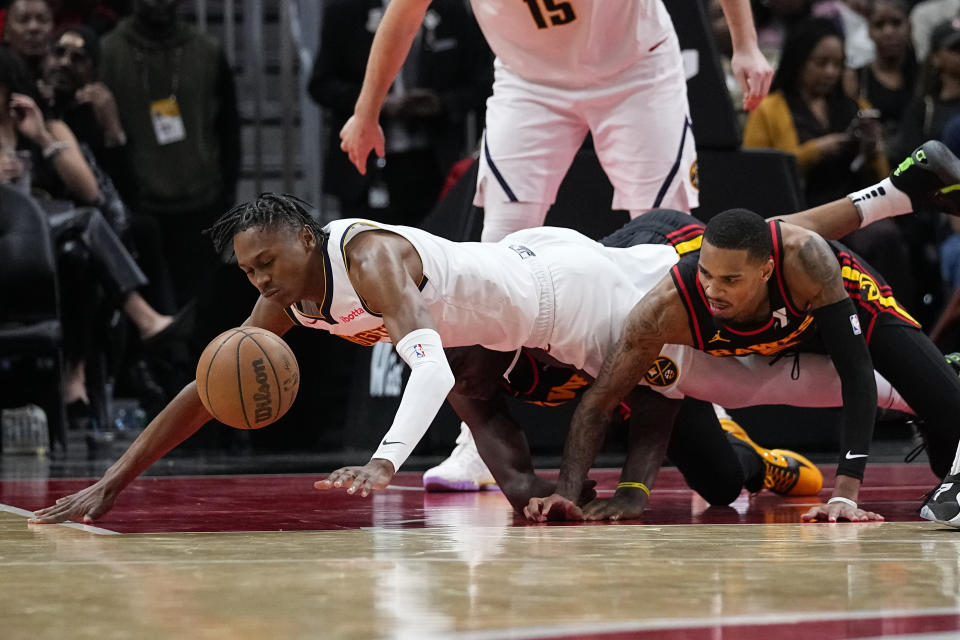 Denver Nuggets forward Peyton Watson (8) and Atlanta Hawks guard Dejounte Murray (5) dive for the ball during the second half of an NBA basketball game, Monday, Dec. 11, 2023, in Atlanta. (AP Photo/John Bazemore)