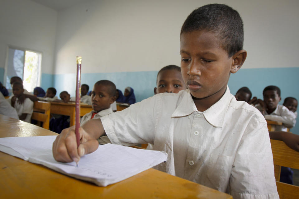 In this photo taken Wednesday, Jan. 15, 2014, Mohamed Aden, 11, works on his exercises inside a school classroom in Mogadishu, Somalia. Officials say more than 35,000 children have been enrolled in a donor-funded program dubbed "Go2School" offering free education in Somalia since it was launched last year, proving popular with parents and children who otherwise would not go to school, but the country’s al-Qaida-linked militant group al-Shabab has issued a new threat against the program, saying it secularizes children. (AP Photo/Farah Abdi Warsameh)