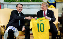 Brazil's President Jair Bolsonaro presents a Brazil naitonal soccer team jersey to U.S. President Donald Trump after Trump gave him a U.S. soccer team jersey during a meeting in the Oval Office of the White House in Washington, U.S., March 19, 2019. REUTERS/Kevin Lamarque