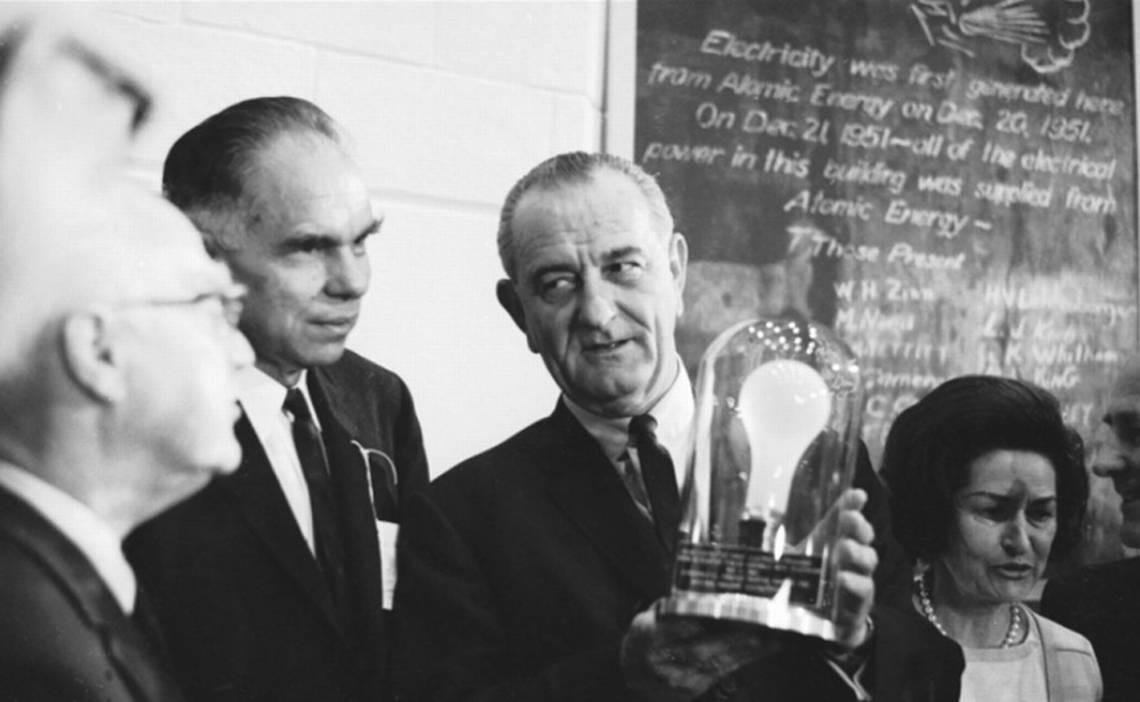 President Lyndon B. Johnson holds one of the light bulbs that were the first in the world to be lit by nuclear energy.