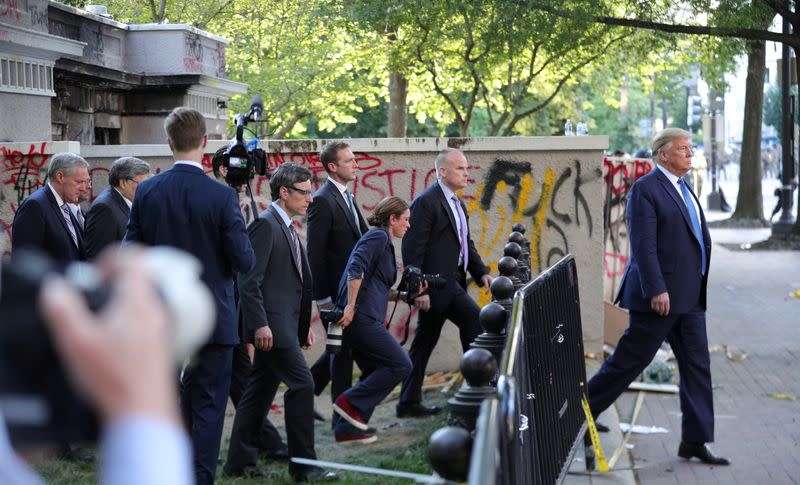 FILE PHOTO: FILE PHOTO: U.S. President Trump walks past a building defaced with graffiti by protestors in Washington