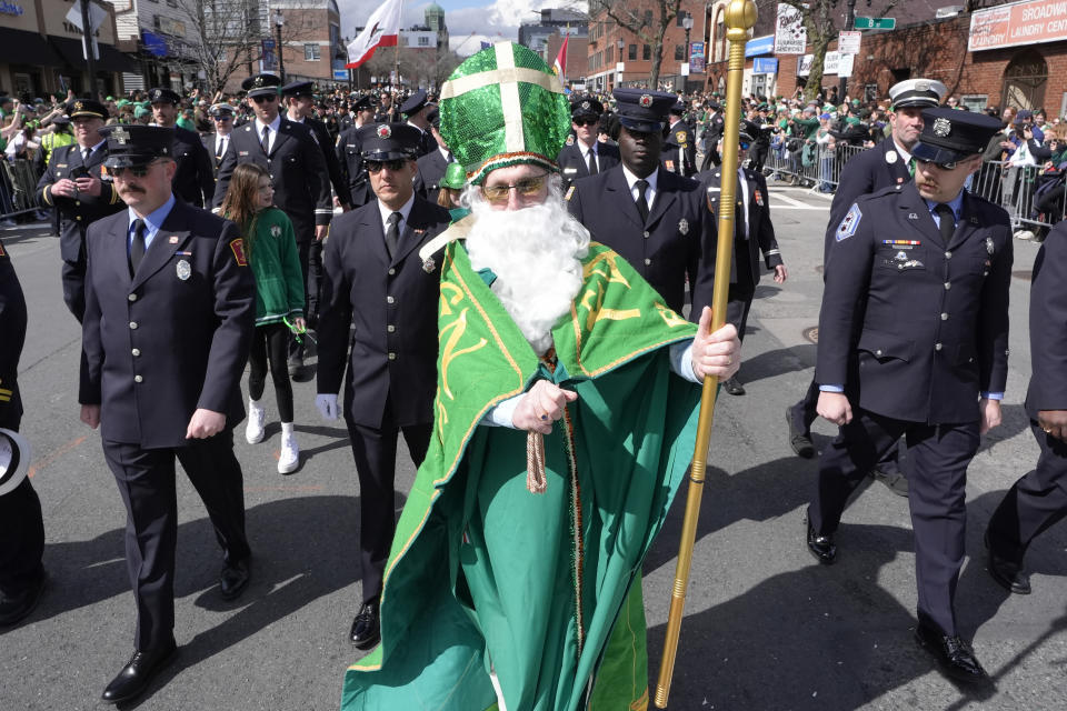 Un hombre vestido de San Patricio camina con un grupo de bomberos durante el desfile del Día de San Patricio, el domingo 17 de marzo de 2024, en el barrio de South Boston, en Boston. (Foto AP/Steven Senne)