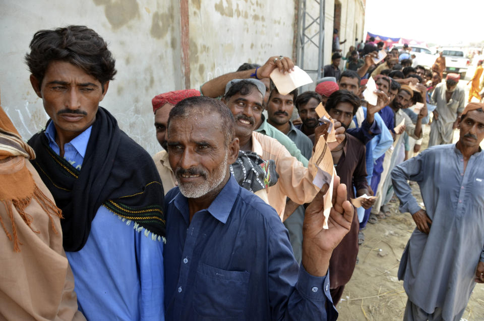 Displaced families, who fled their flood-hit homes, line up to get relief aid in Jaffarabad, a district of Baluchistan province, Pakistan, Wednesday, Sept. 21, 2022. Devastating floods in Pakistan's worst-hit province have killed 10 more people in the past day, including four children, officials said Wednesday as the U.N. children's agency renewed its appeal for $39 million to help the most vulnerable flood victims. (AP Photo/Zahid Hussain)