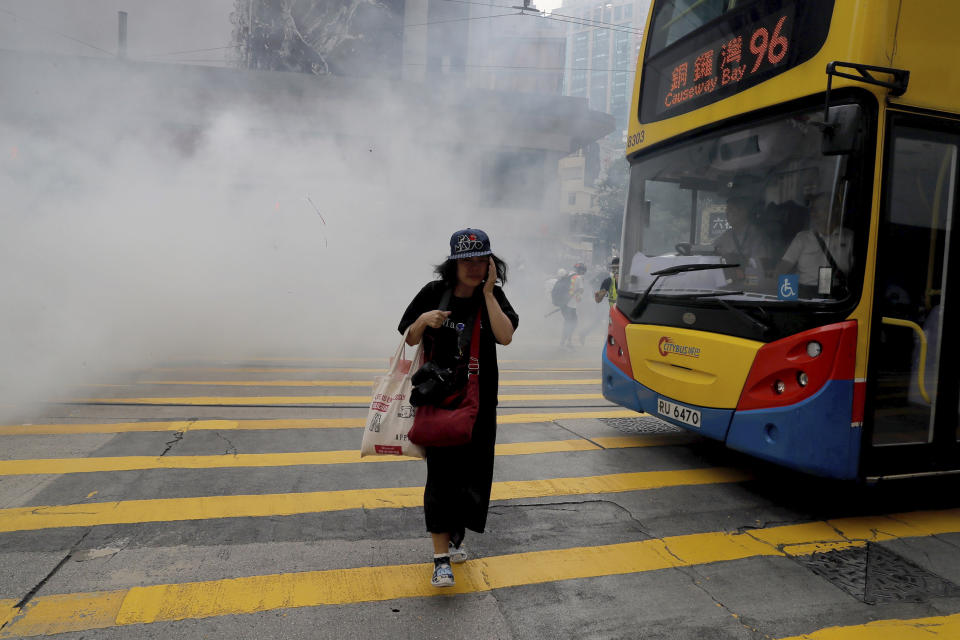 A woman walks near tear gas during a protest in Hong Kong on Sunday, Sept. 29, 2019. Sunday's gathering of protesters, a continuation of monthslong protests for greater democracy, is part of global "anti-totalitarianism" rallies planned in over 60 cities worldwide to denounce "Chinese tyranny." (AP Photo/Kin Cheung)