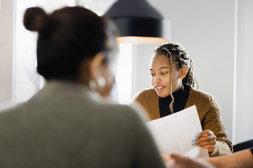 Female candidate giving her resume to HR manager during a job interview in office. Woman candidate interview with HR manager in office.