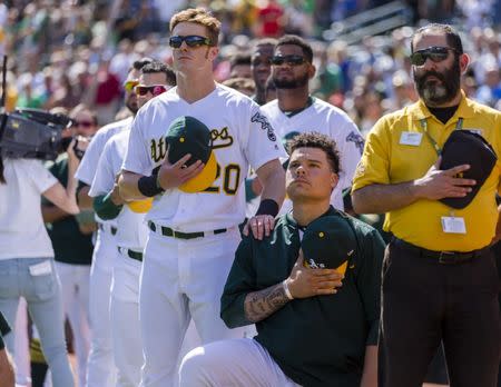 Sep 24, 2017; Oakland, CA, USA; Oakland Athletics catcher Bruce Maxwell (13) kneels during the national anthem as right fielder Mark Canha (20) places his hand on his shoulder before a game against the Texas Rangers at Oakland Coliseum. Mandatory Credit: John Hefti-USA TODAY Sports