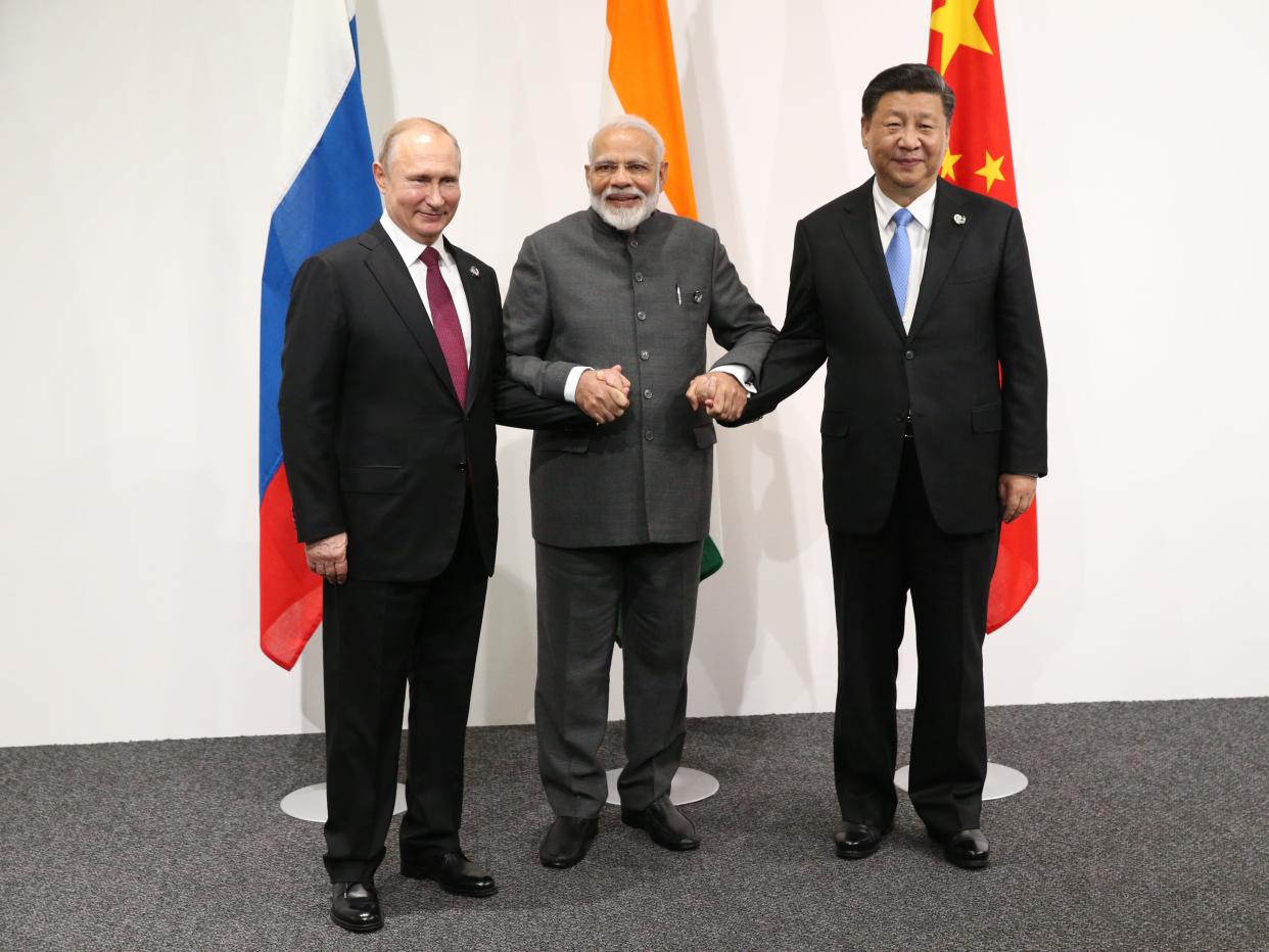 Russian President Vladimir Putin (L), Indian Prime Minister Narendra Modi (C) and Chinese President Xi Jinping (R) in front of respective country flags.