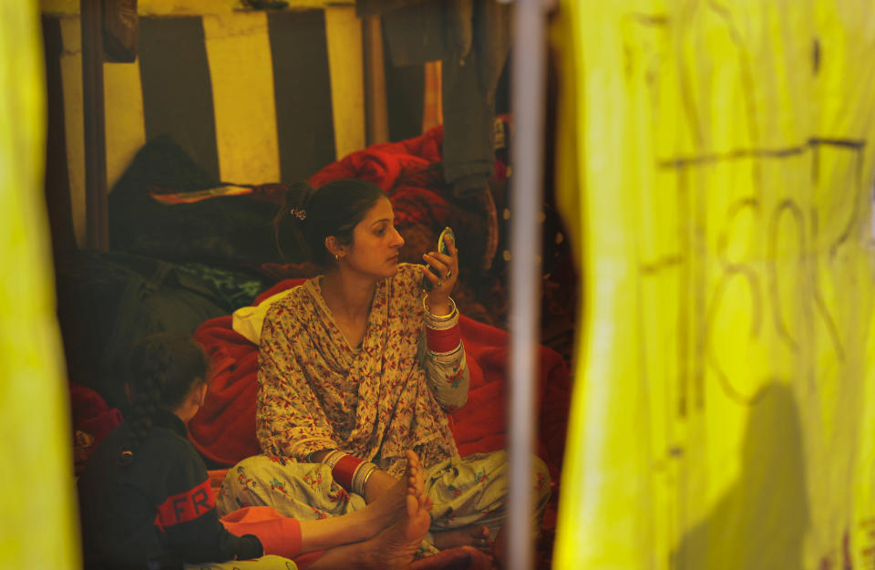 A newly wed woman looks in a mirror as she joins her farmer husband for a protest in a makeshift tent in one of the three main protest sites outside New Delhi's border, India, Friday, Feb. 5, 2021. India's agriculture minister on Friday defended the new agriculture reform laws in Parliament, dampening hopes of any quick settlement with tens of thousands of protesting farmers demanding their repeal by blocking three highways connecting New Delhi to northern India for over two months now. (AP Photo/Manish Swarup)