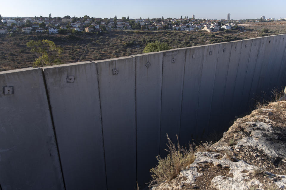 The Israeli settlement of Hashmona'im is seen behind a section of Israel's separation barrier, in the West Bank village of Nilin, west of Ramallah, Sunday, Nov. 7, 2021. Nearly two decades after Israel sparked controversy worldwide by building the barrier during a Palestinian uprising, it has become a seemingly permanent feature of the landscape — even as Israel encourages its citizens to settle on both sides. (AP Photo/Nasser Nasser)