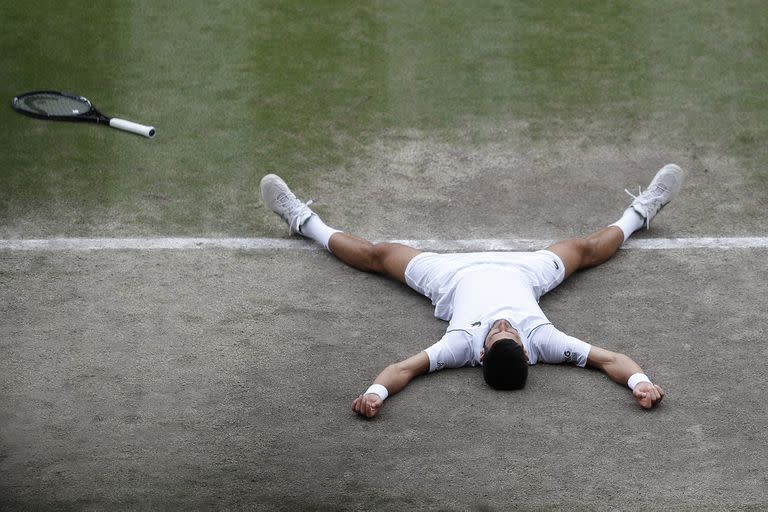 El serbio Novak Djokovic se derrumba mientras celebra después de derrotar al italiano Matteo Berrettini en la final masculina individual el día trece del Campeonato de Tenis de Wimbledon en Londres, el domingo 11 de julio de 2021