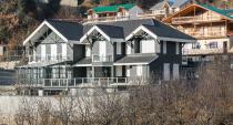 The home's grey-tiled exterior blends into the natural surroundings; its muted palette ironically stands apart from the neighbouring houses.