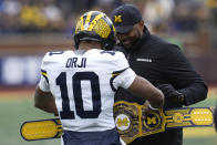 Michigan quarterback Alex Orji (10) shows head coach Sherrone Moore a wrestling belt after scoring a touchdown during the NCAA college football team's spring game in Ann Arbor, Mich., Saturday, April 20, 2024. (AP Photo/Paul Sancya)