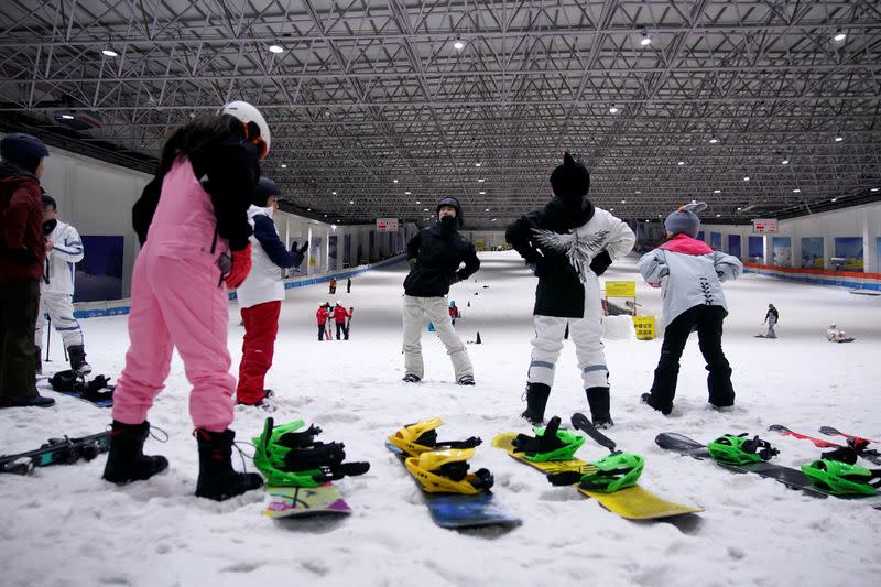 People warm up inside an indoor ski park at Qiaobo Ice and Snow World in Shaoxing