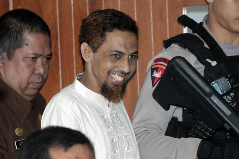 FILE - Indonesian militant Umar Patek, center, smiles as he enters the courtroom to attend his trial at a district court in Jakarta, Indonesia, Monday, Feb. 20, 2012. A bombmaker in the 2002 Bali attack that killed 202 people has walked free from an Indonesian prison Wednesday. Dec. 7, 2022 after serving half of a 20-year sentence, despite upsetting Australia’s leader who described him as “abhorrent.” Umar Patek, 55, whose real name is Hisyam bin Alizein, was a leading member of the al Qaida-linked network Jemaah Islamiyah. (AP Photo/Tatan Syuflana, File)