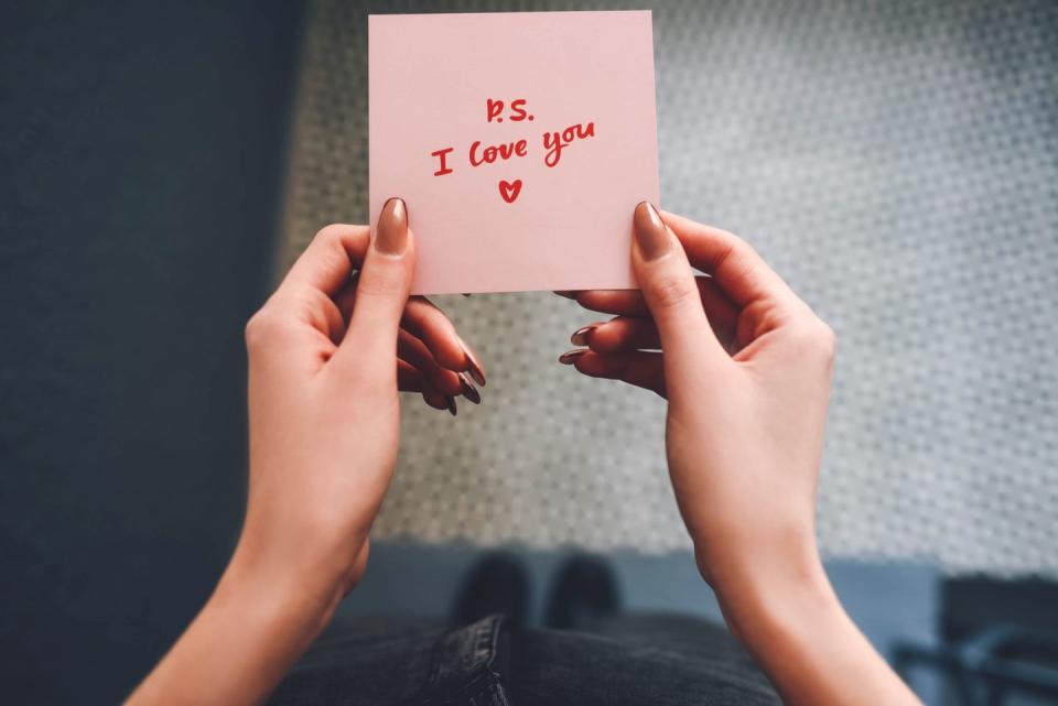 the girl holds a pink love note in her hands valentine's day gray background woman's hand declaration of love love note confession note girl with a note