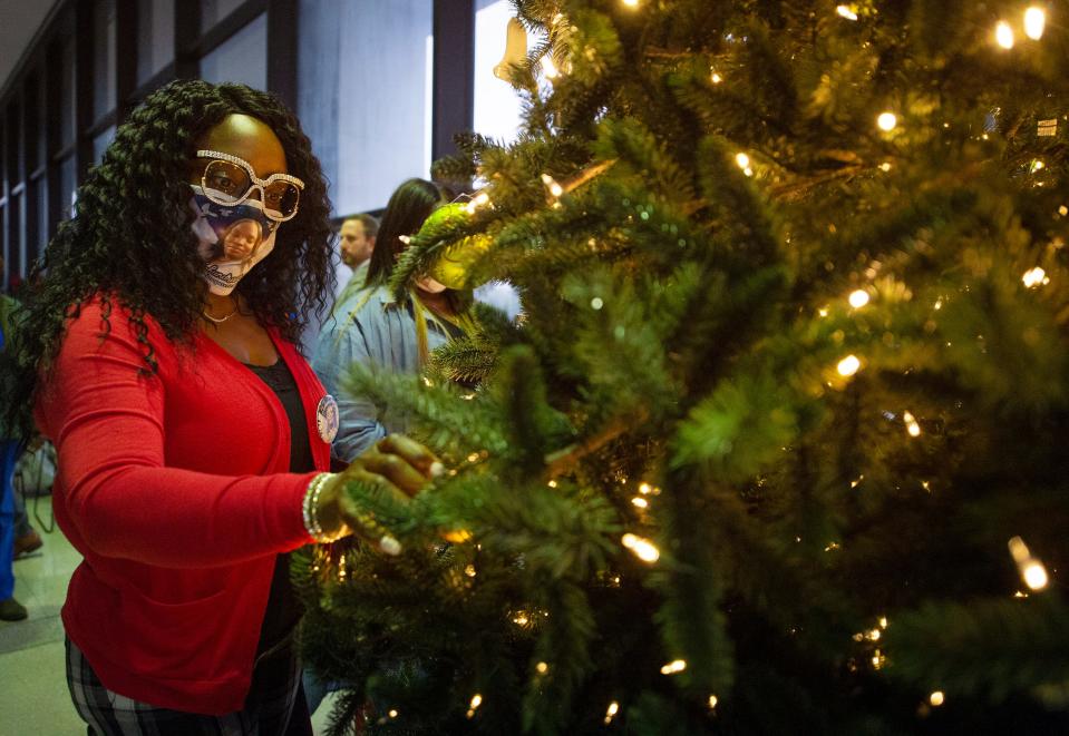 Felicia Harper hangs an ornament in honor of her niece, Teshundra Fortune, during the 2021 Crime Victims Christmas Tree Dedication at the Walter Sillers State Office Building in Jackson, Miss., Monday, Dec. 6, 2021. Teshundra was killed in west Jackson in March 2021. Attorney General Lynn Fitch hosted the dedication for crime victims in the state.