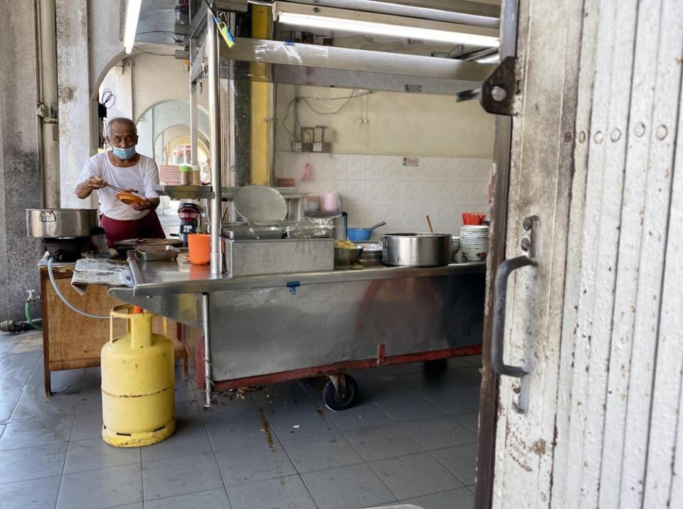 Ong Tai Buan dishing out the side dishes to be served to customers at his stall.