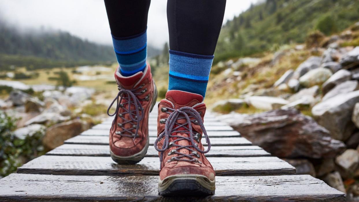  A person walking over a bridge in hiking boots. 