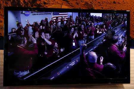 The mission control team at NASA's Jet Propulsion Laboratory (JPL) react on a video screen as the spaceship Insight, NASA's first robotic lander dedicated to studying the deep interior of Mars, lands on the planet's surface after a six-month journey, in Pasadena, California, U.S. November 26, 2018. REUTERS/Mike Blake