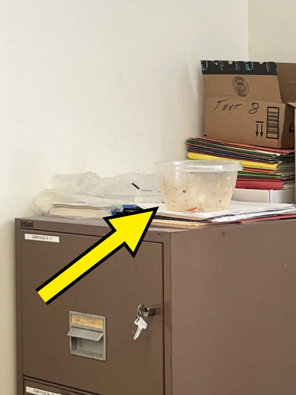 An empty, dirty Tupperware container has been left on top of the office's filing cabinets