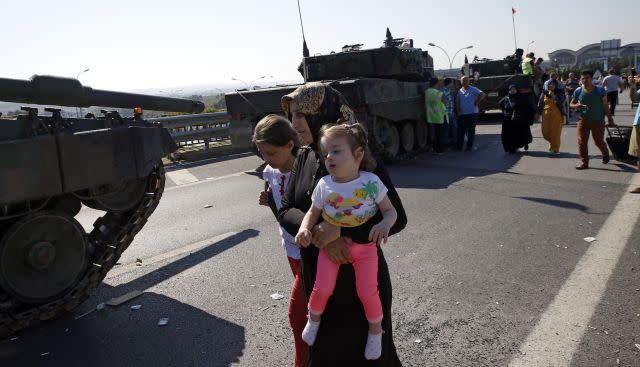 A woman with two girls walks past military vehicles in Istanbul the day after the attempted coup.