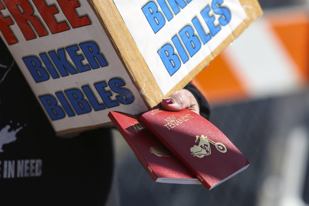 A woman hands out “Biker Bibles” to people along Main Street in Daytona, FL during Bike Week on March 5, 2021. (Sam Thomas/Orlando Sentinel)