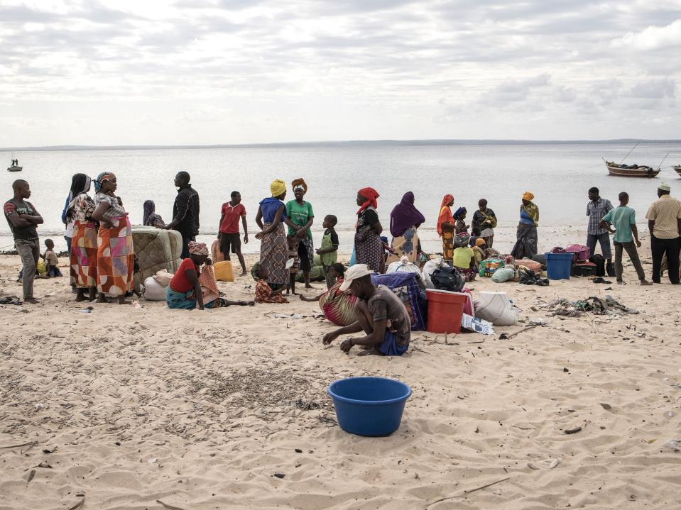 People gather with their belongings as they arrive at Paquitequete beach in Pemba on 22 May 2021 after fleeing Palma by boat (John Wessels/AFP via Getty Images)